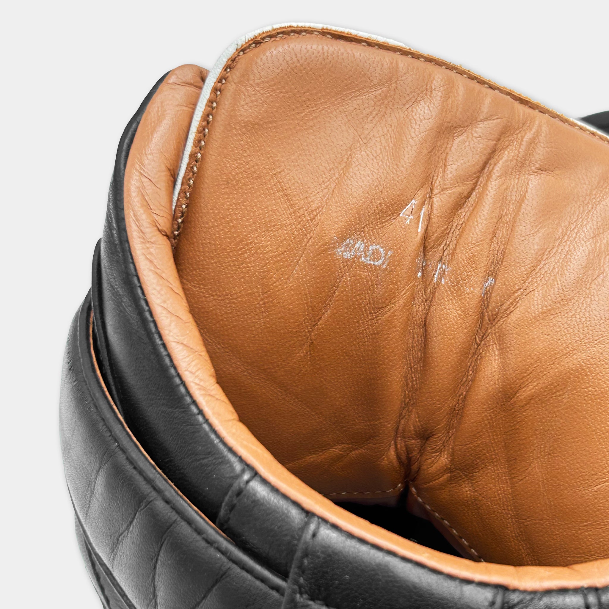 the interior of a leather shoe, specifically the inside of a black and brown leather shoe.