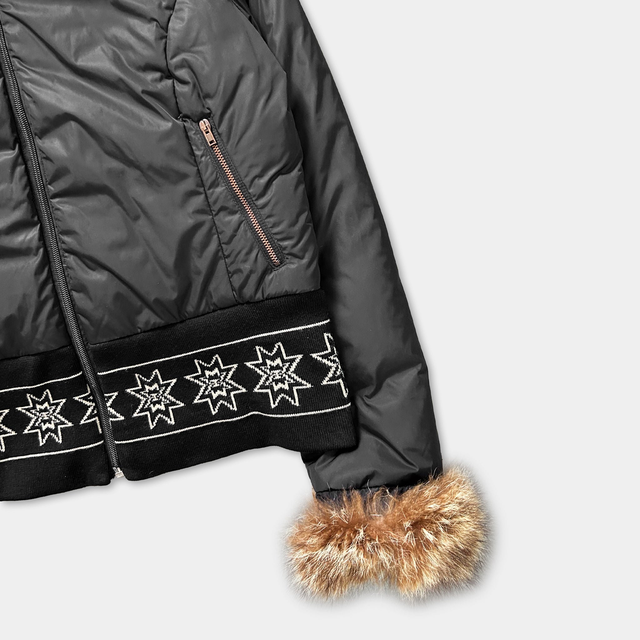 A black puffer jacket with a fur trim and a pattern of white stars on the front.