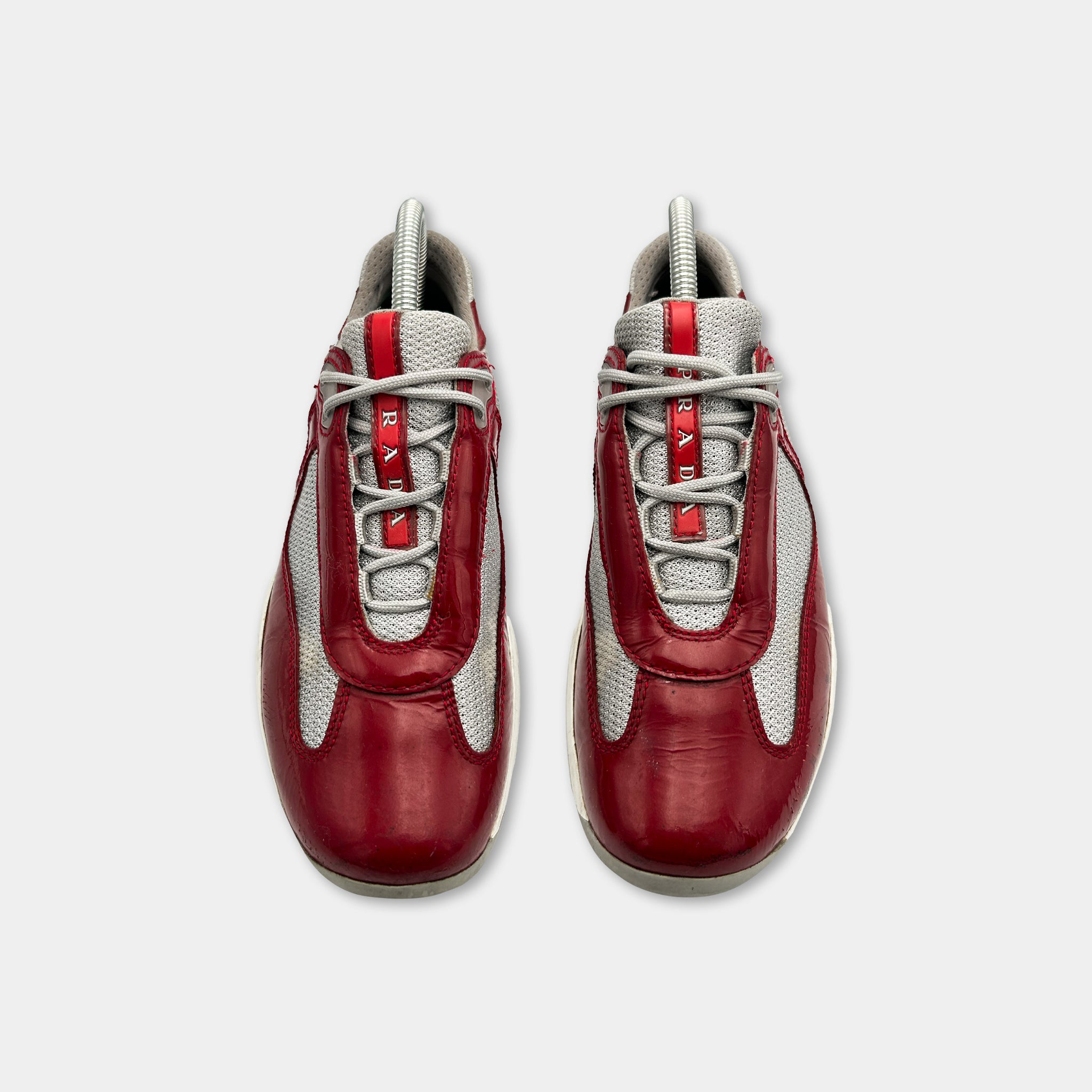 A pair of red and gray athletic shoes with white laces and soles.