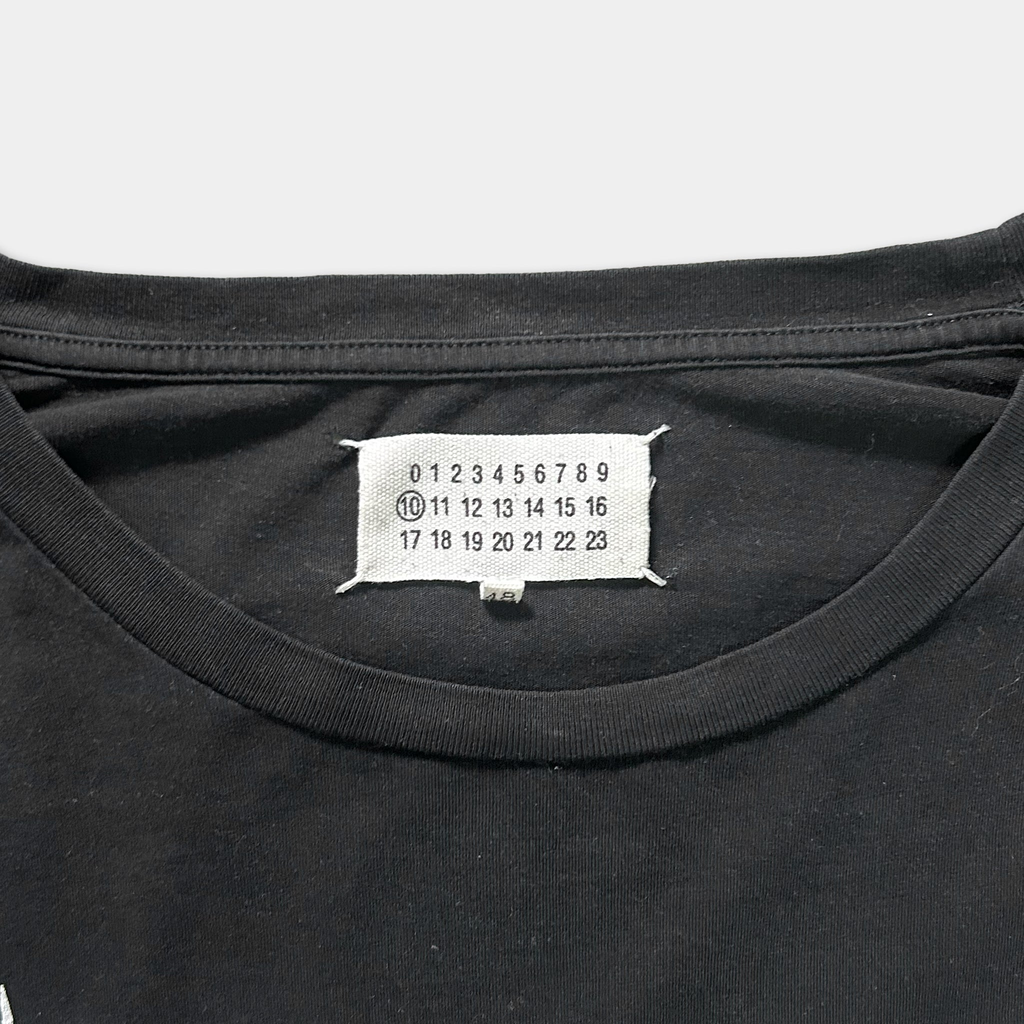 a close-up view of a black t-shirt with a white label on the collar. The label displays numbers and text, but the image does not contain any text that can be described in fewer than 500 characters.
