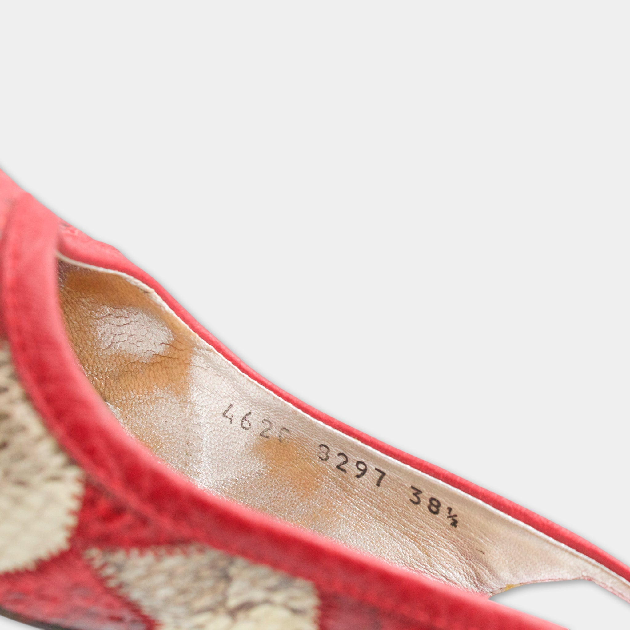 A close-up view of a red shoe with a white sole, showing the brand name and model number printed on the inside of the shoe.