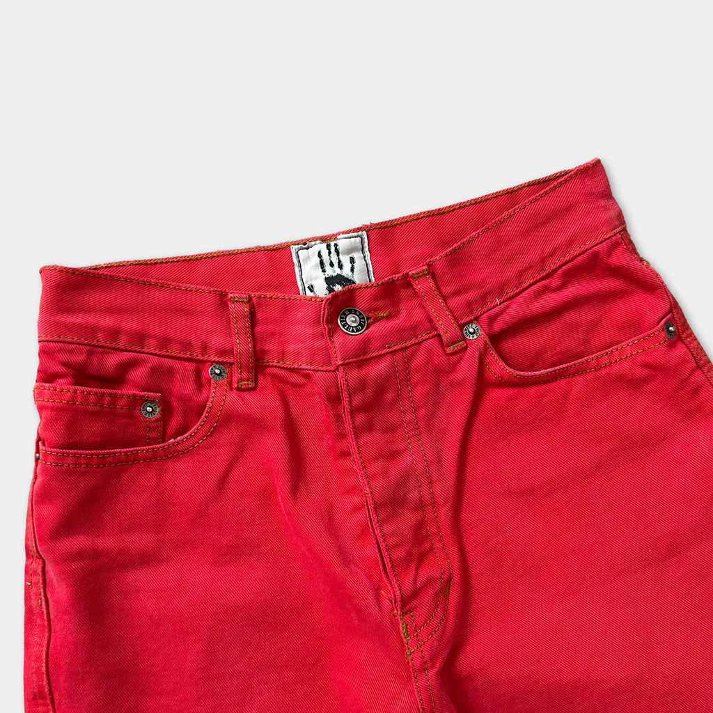 A pair of bright red jeans with a label on the waistband.