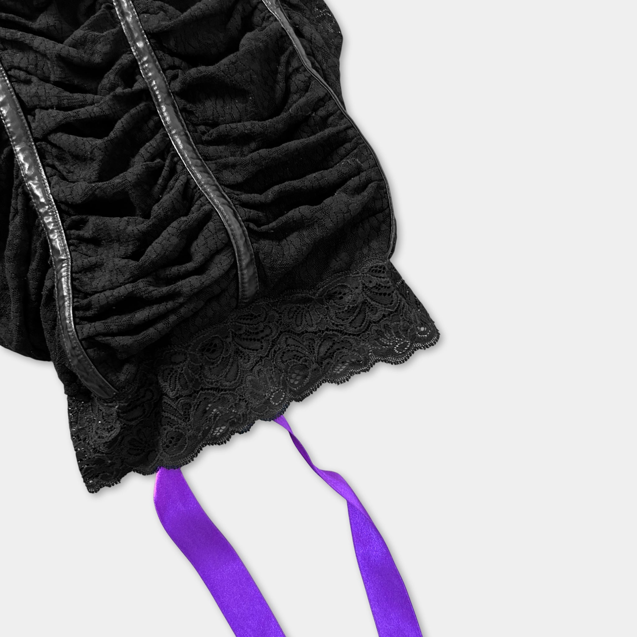 a close-up view of a black lace top with a purple ribbon tied around it.