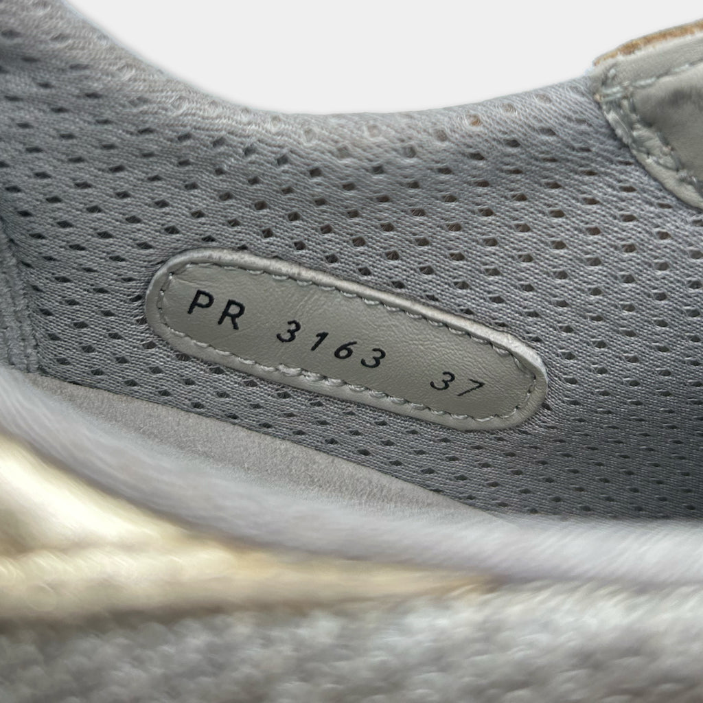 A close-up view of a gray and white shoe, showing the brand name and model number PR 3163 37 printed on the side of the shoe.