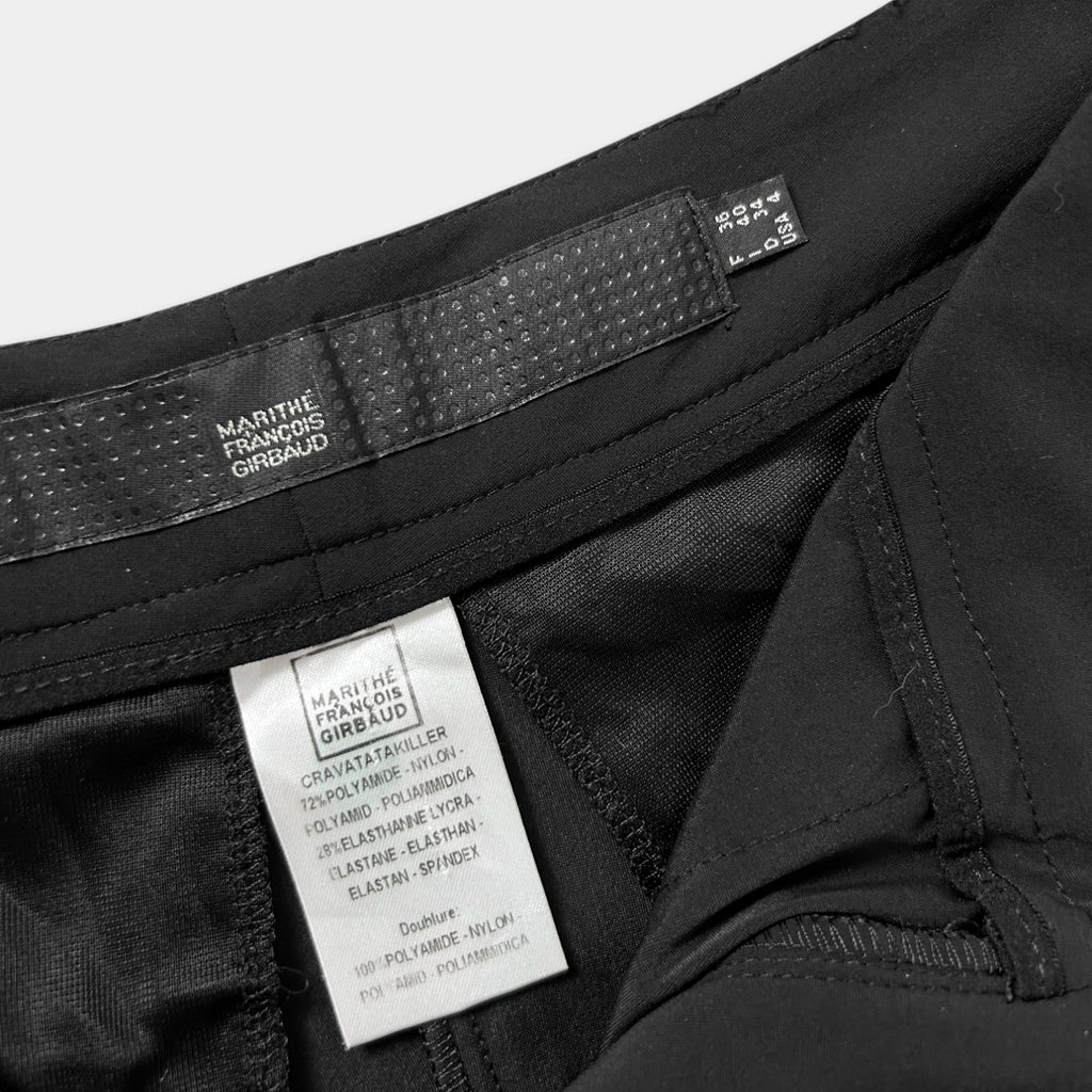 a close-up view of a black garment, possibly a pair of pants or shorts, with a label attached to it. The label appears to contain text and information about the garment, such as the brand, size, and material.