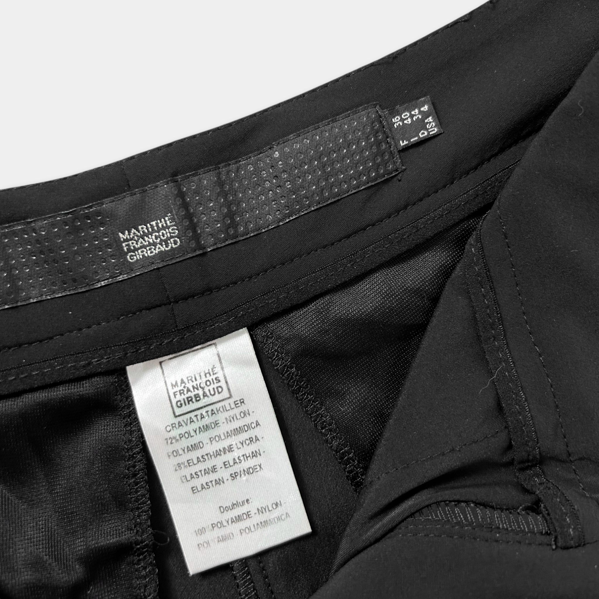 a close-up view of a black garment, possibly a pair of pants or shorts, with a label attached to it. The label appears to contain text and information about the garment, such as the brand, size, and material.