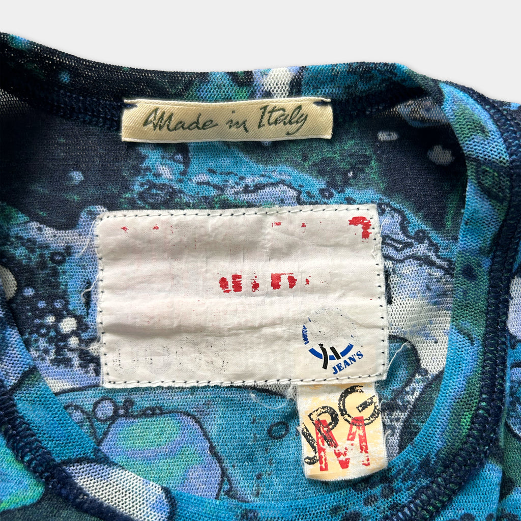 a close-up view of a colorful patterned fabric, possibly a shirt or garment, with a label attached to it. The label appears to be a handmade tag, indicating that the item was made in Italy.