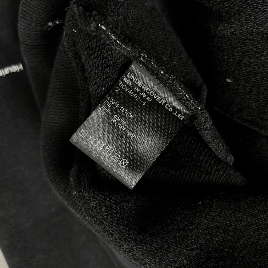 a close-up view of a black fabric, possibly a sweater or garment, with a label attached to it. The label appears to contain information about the fabric, such as the brand, material, and care instructions.