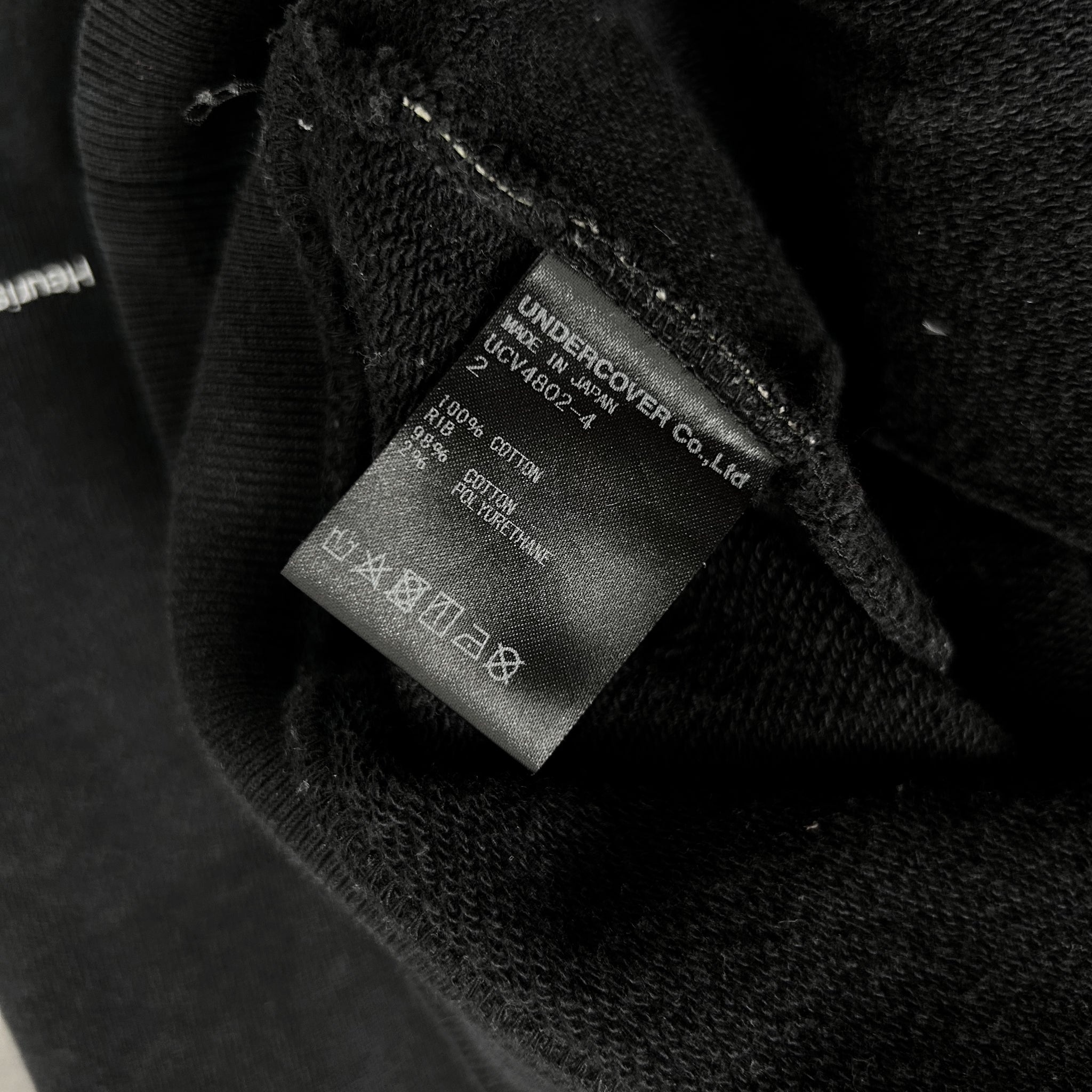 a close-up view of a black fabric, possibly a sweater or garment, with a label attached to it. The label appears to contain information about the fabric, such as the brand, material, and care instructions.