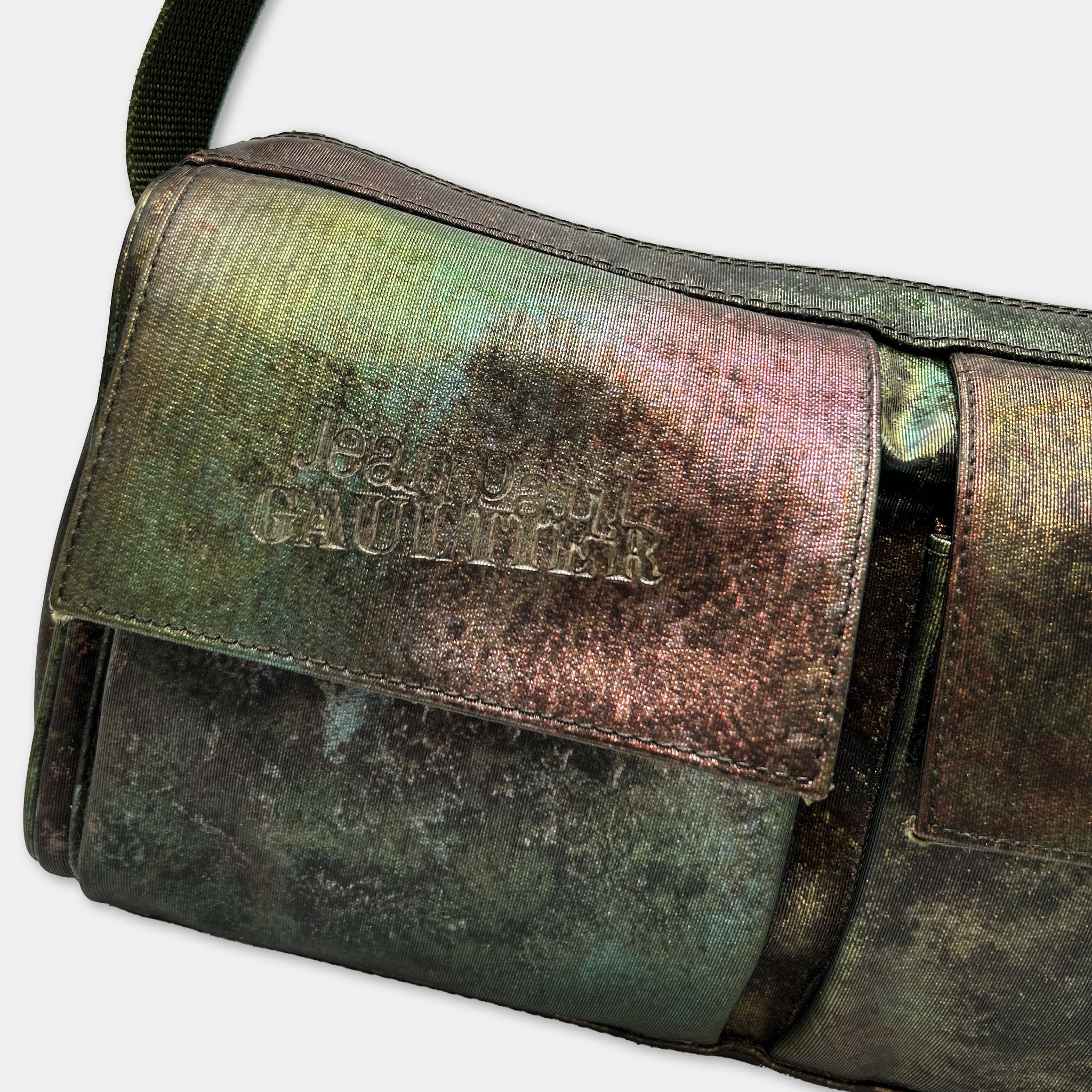 A close-up image of a green and brown leather bag with embossed text on it.