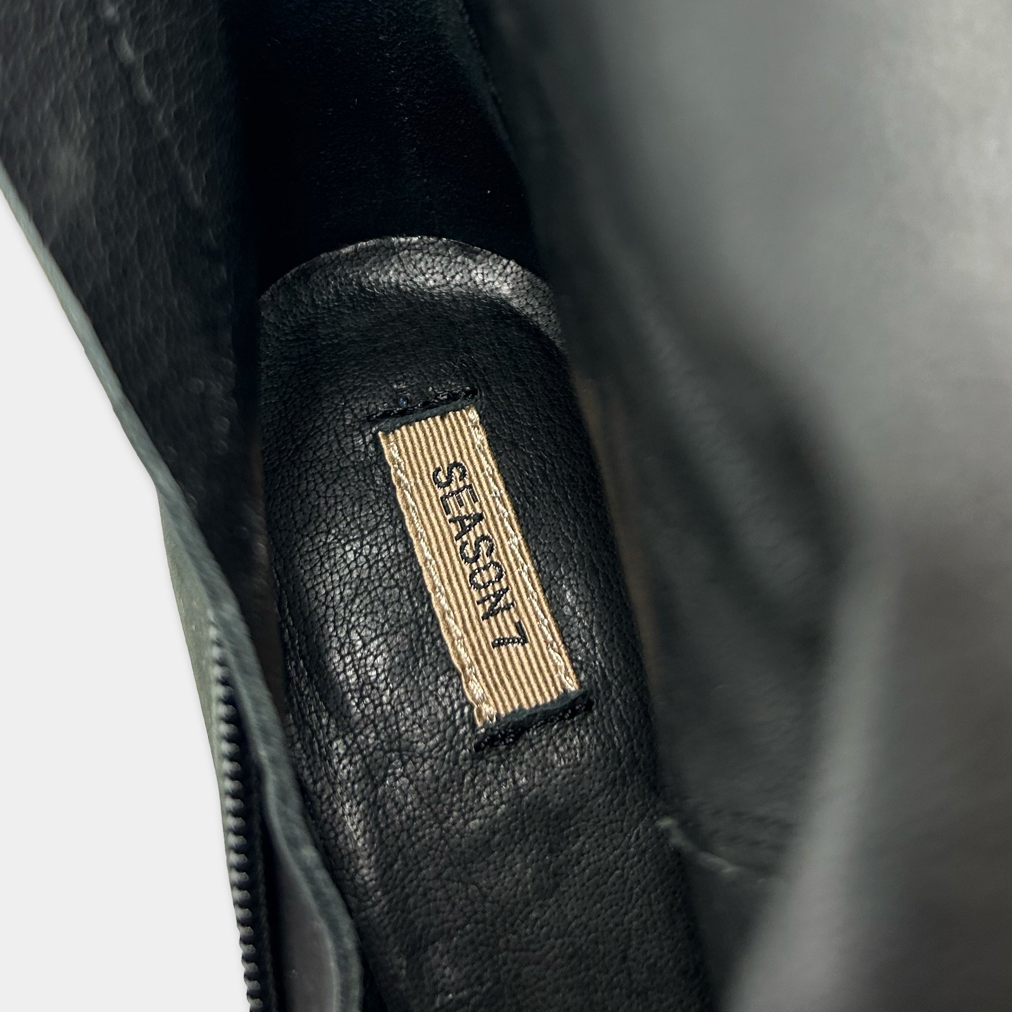 A close-up view of a black leather shoe, with a label or tag attached to it.