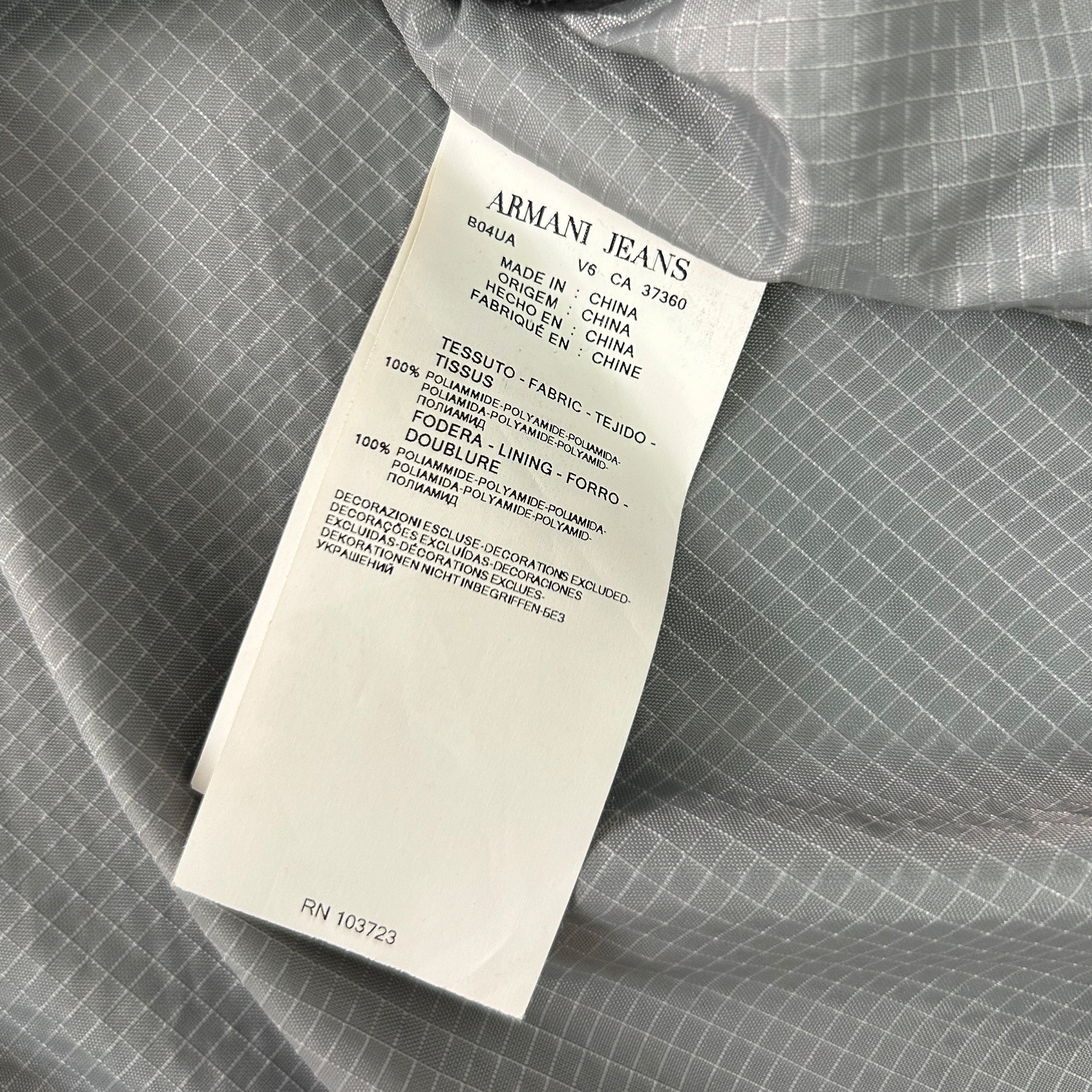 a close-up view of a white label attached to a gray fabric, possibly a piece of clothing.