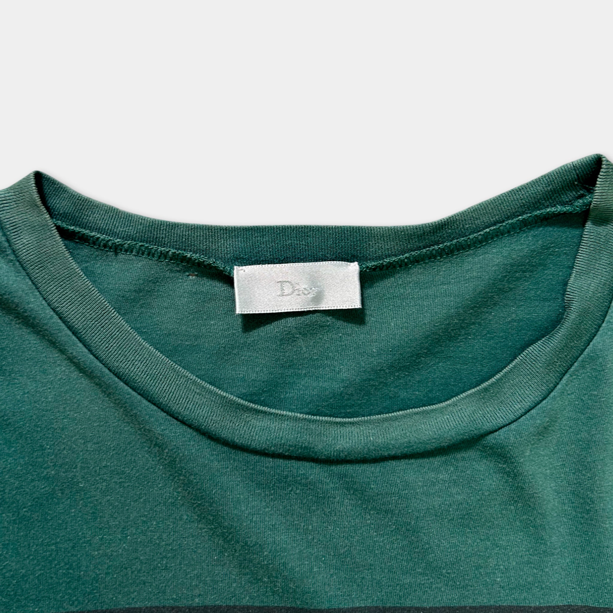 A close-up view of a green t-shirt with a white label on the collar.