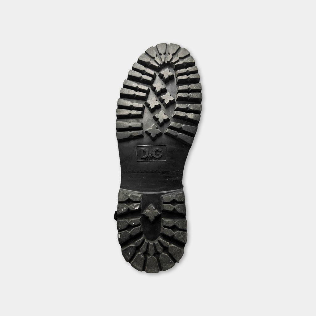 A close-up view of a black rubber sole of a shoe, with the brand name "D&G" printed on it.