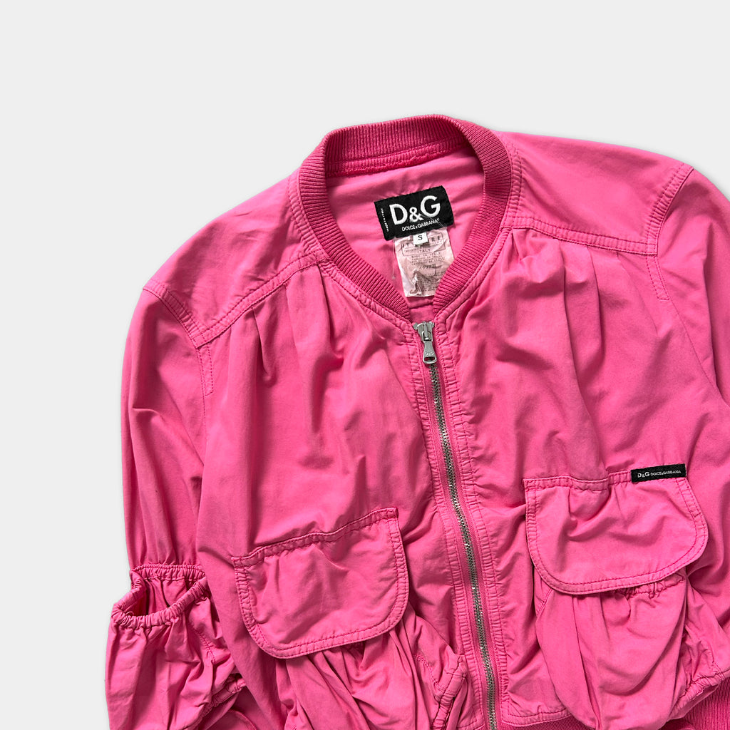 A bright pink jacket with a collar and zipper, featuring a D&G logo on the chest.
