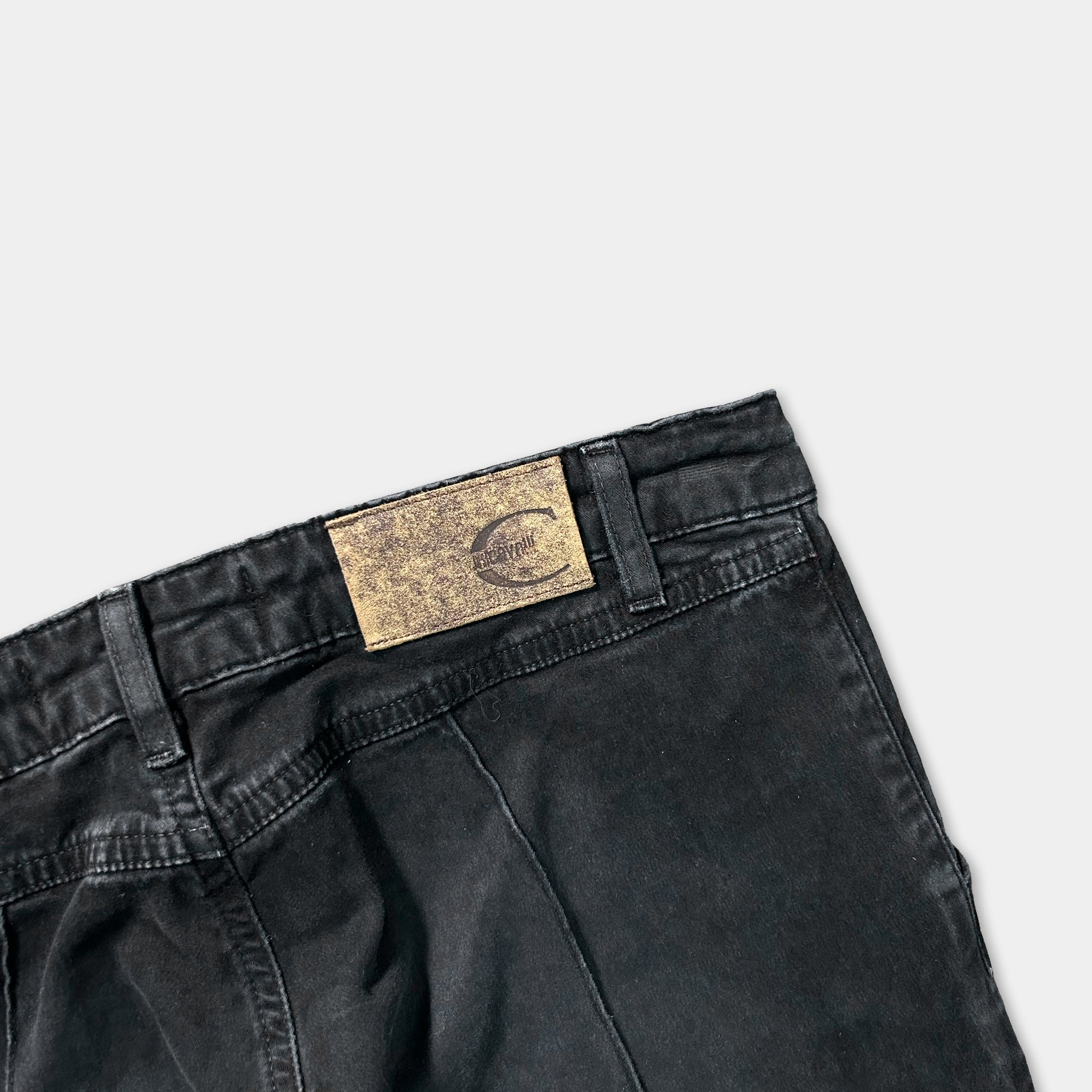 A pair of black jeans with a worn-out label on the back pocket.