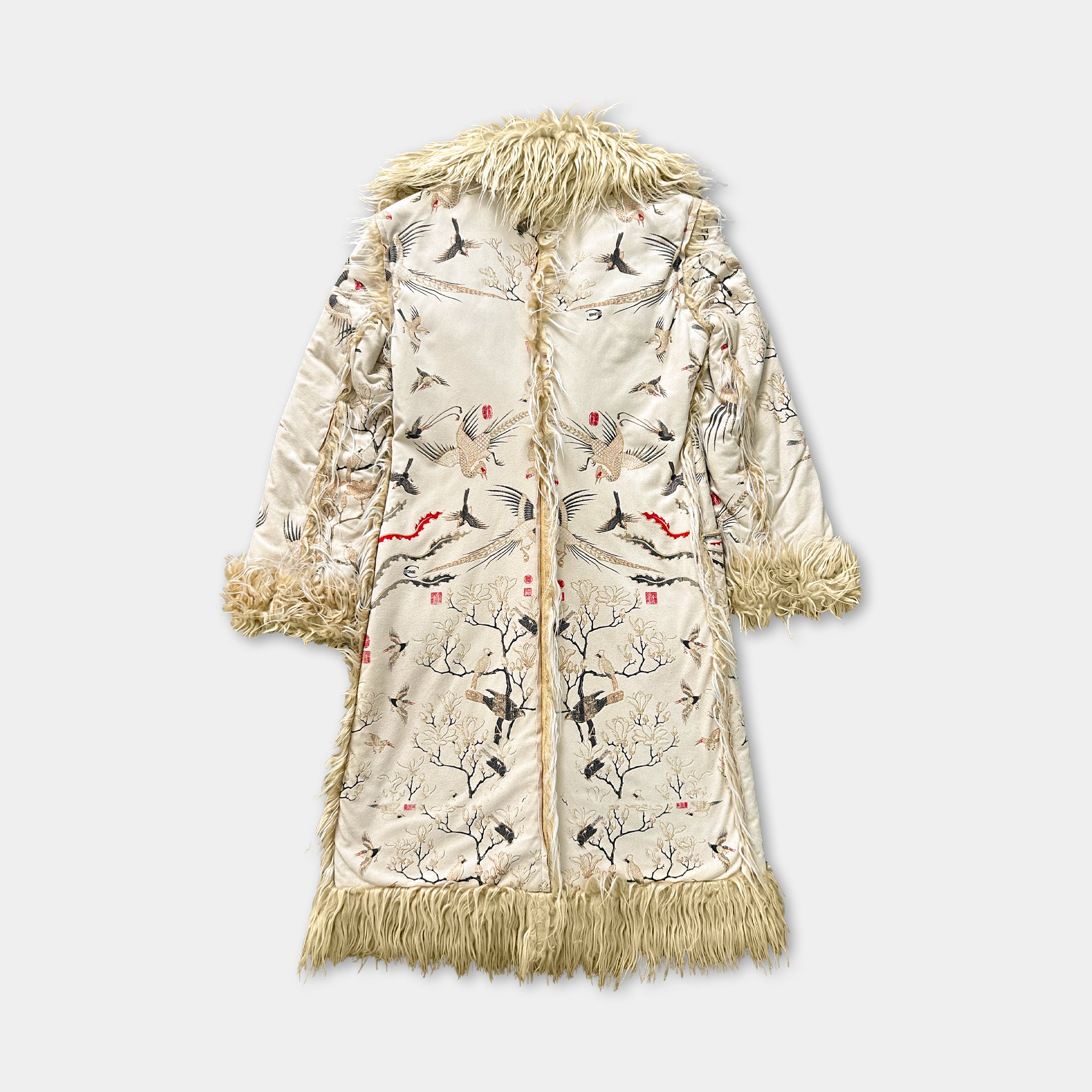 A beige coat with a fur collar and fringe, adorned with a pattern of birds and trees.