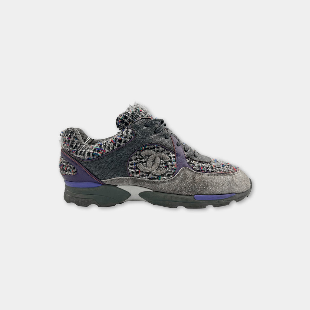 A pair of grey and purple Chanel sneakers with a multicolored woven pattern.