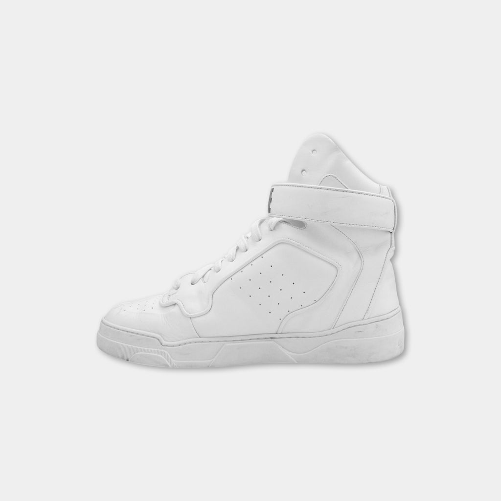 A white high-top sneaker with a strap and laces.