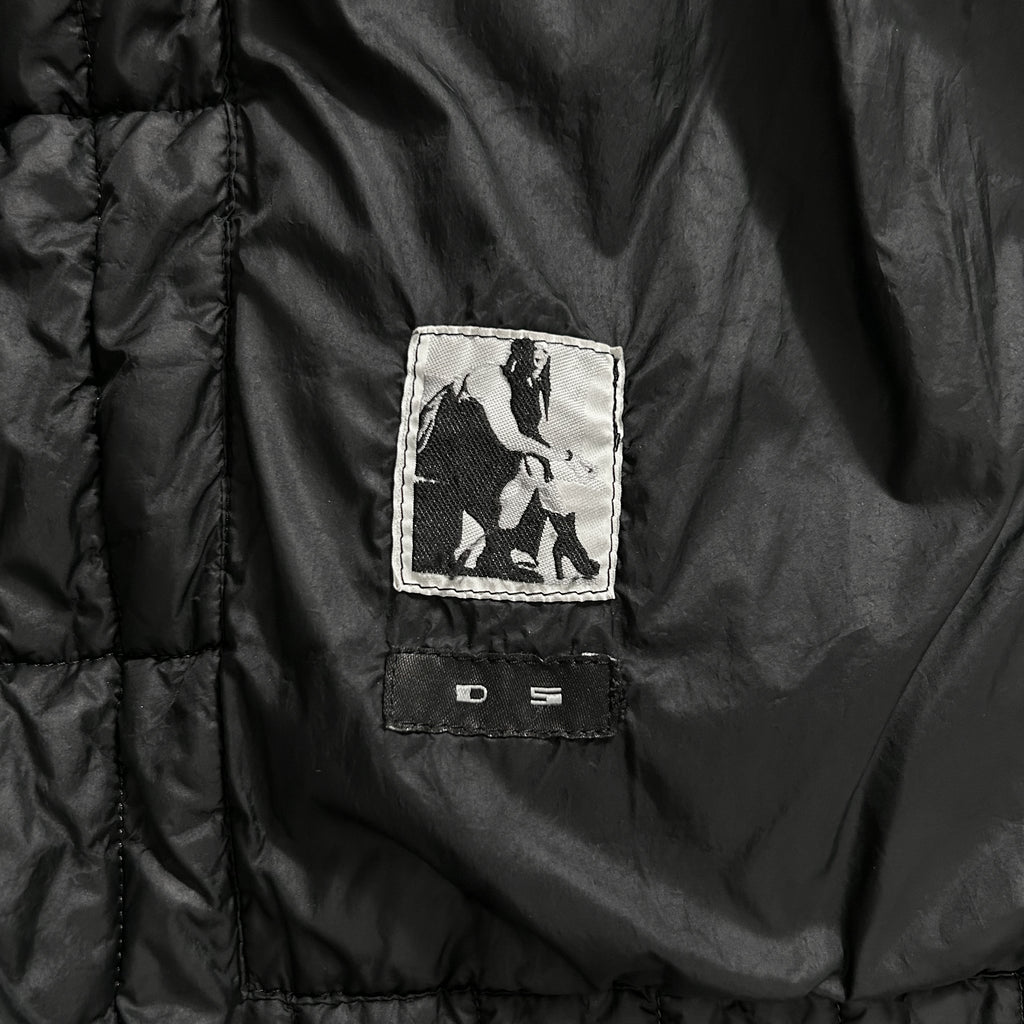 a close-up view of a black jacket with a small patch on the left side featuring a black and white image of a person.