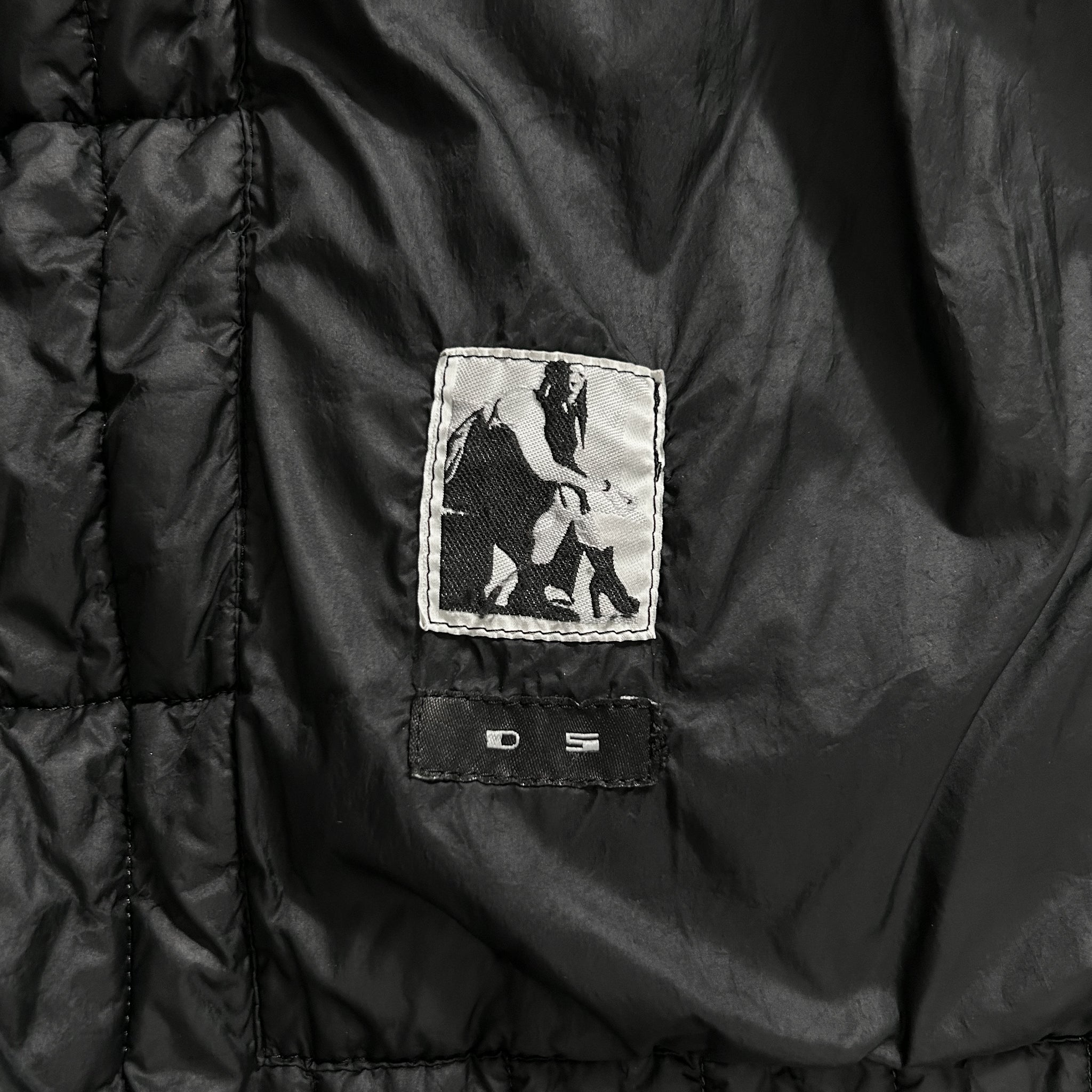 a close-up view of a black jacket with a small patch on the left side featuring a black and white image of a person.