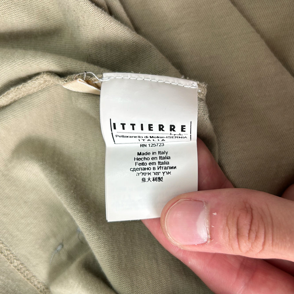 A hand holding a white label with text on it, against a beige background.