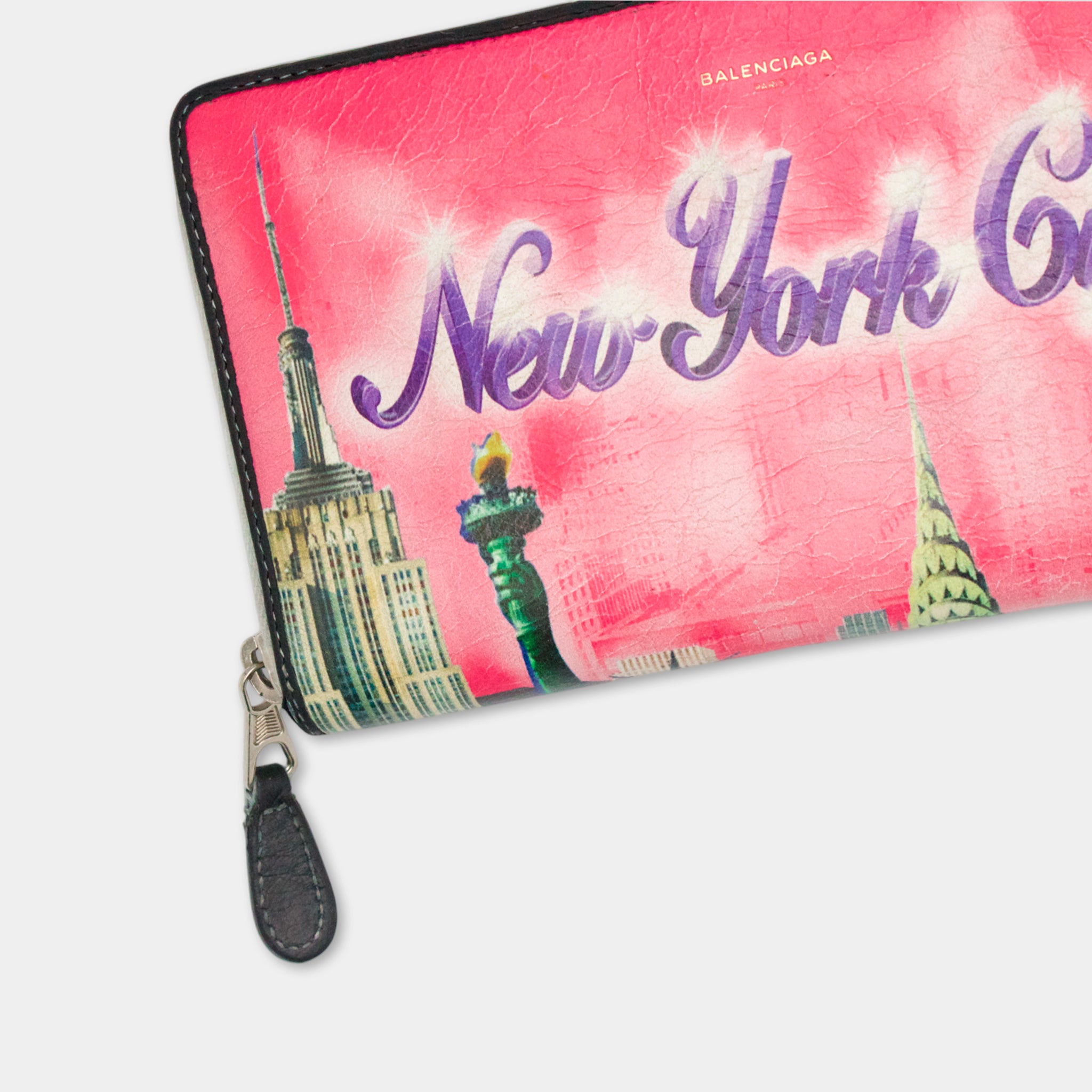 A pink wallet or purse with a printed design of the New York City skyline, including the Empire State Building and other iconic landmarks.