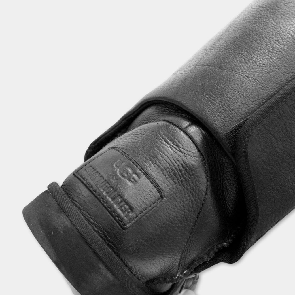 A close-up view of a black leather boot, with the Ugg logo visible on the side.