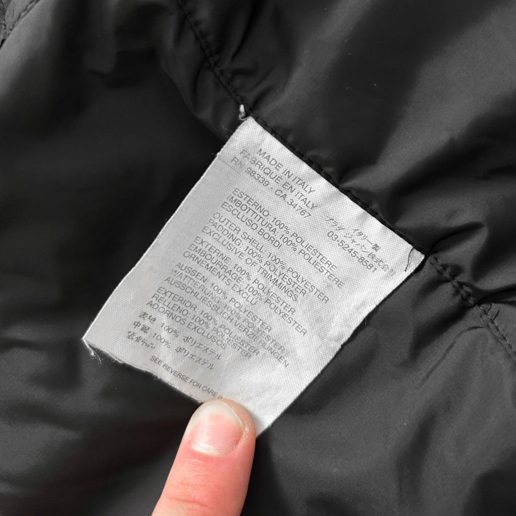 A close-up view of a black fabric, possibly a piece of clothing, with a label attached to it. The label appears to contain text in a foreign language, which is not transcribed due to the language barrier.