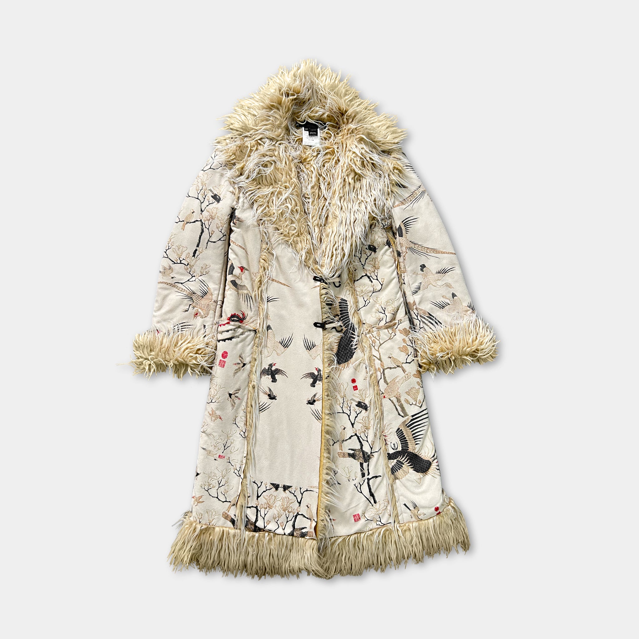 A long, beige coat with a fur collar and fringe, featuring a floral pattern and birds on the fabric.