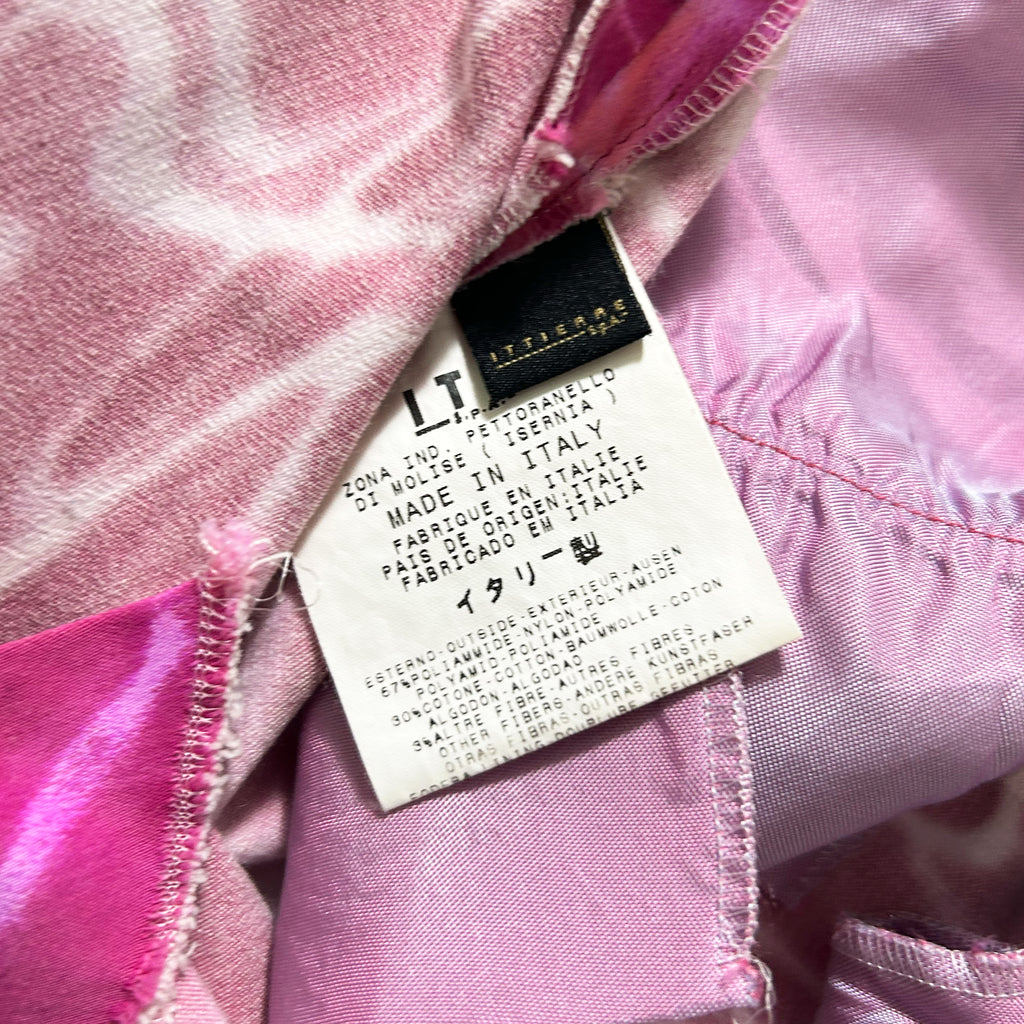 a close-up view of a pink fabric with a label attached to it, which contains text in Italian.