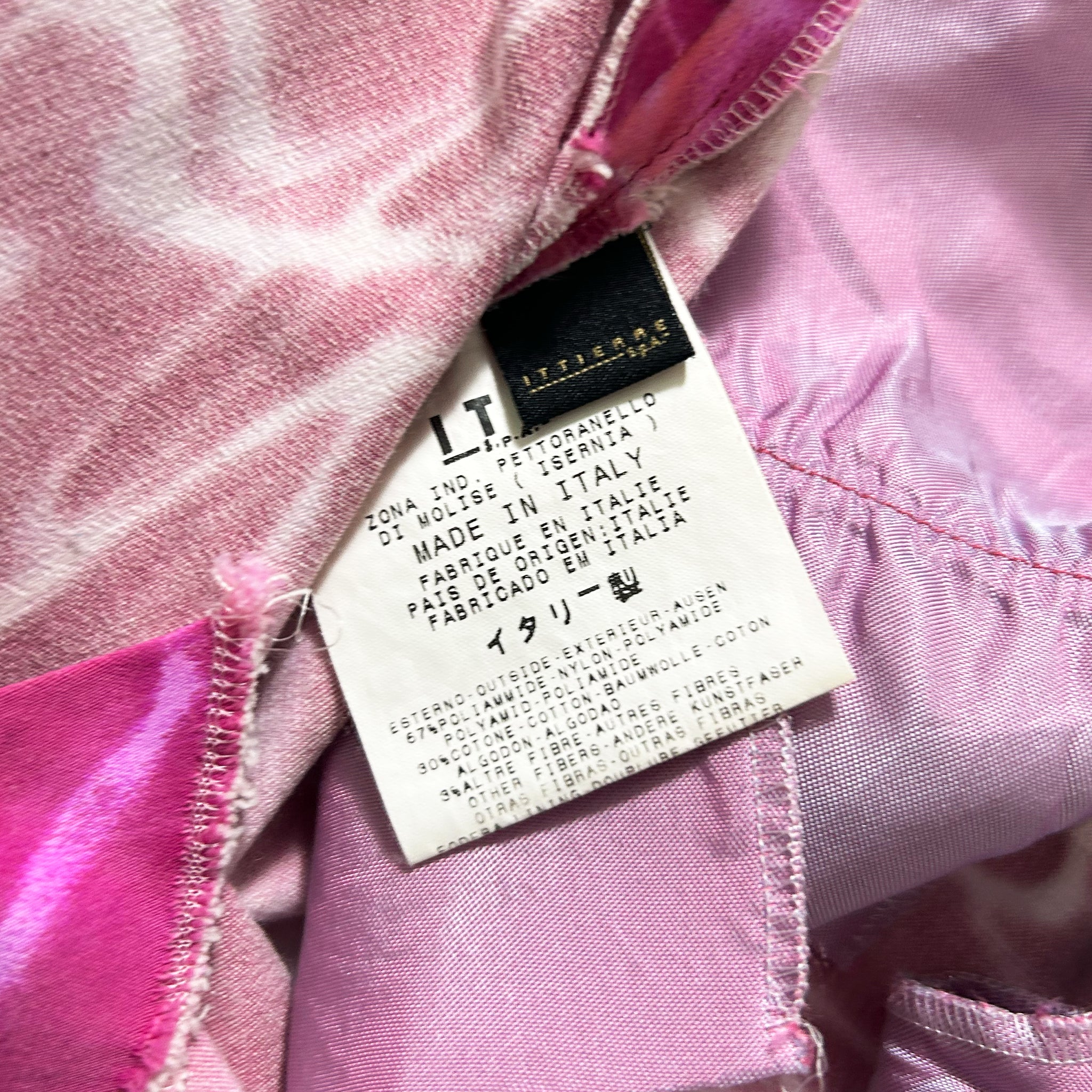 a close-up view of a pink fabric with a label attached to it, which contains text in Italian.