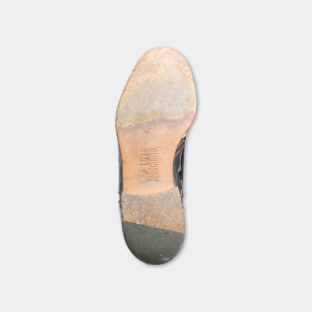 the sole of a worn and dirty shoe against a plain background.