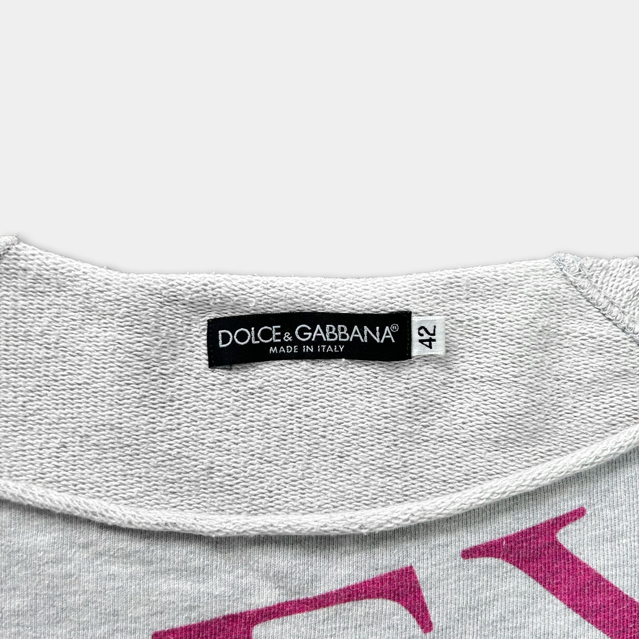 a close-up view of a white sweater with a label on the collar that reads "DOLCE & GABBANA MADE IN ITALY".