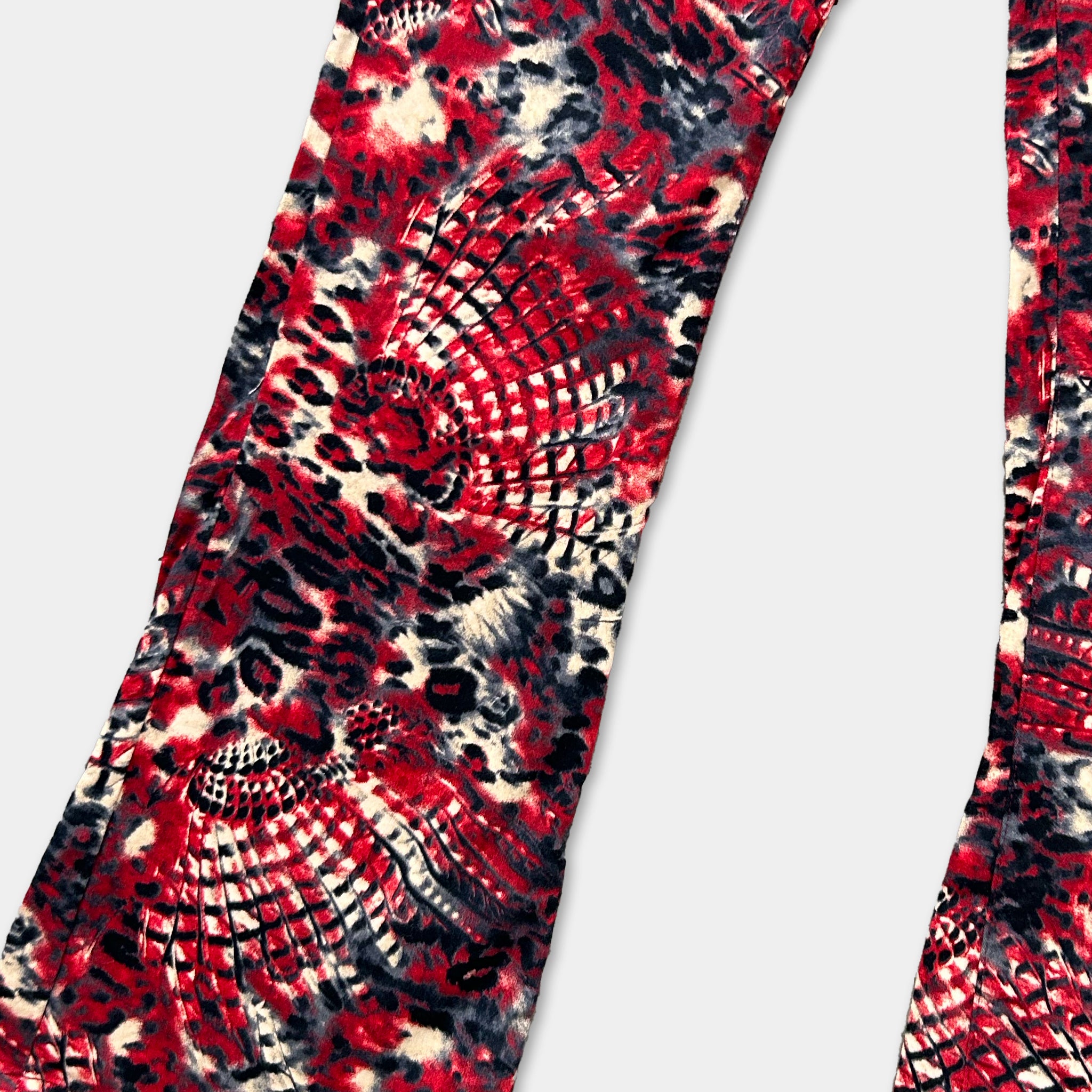 a close-up view of a pair of red and black patterned pants, with a bold, tie-dye design.