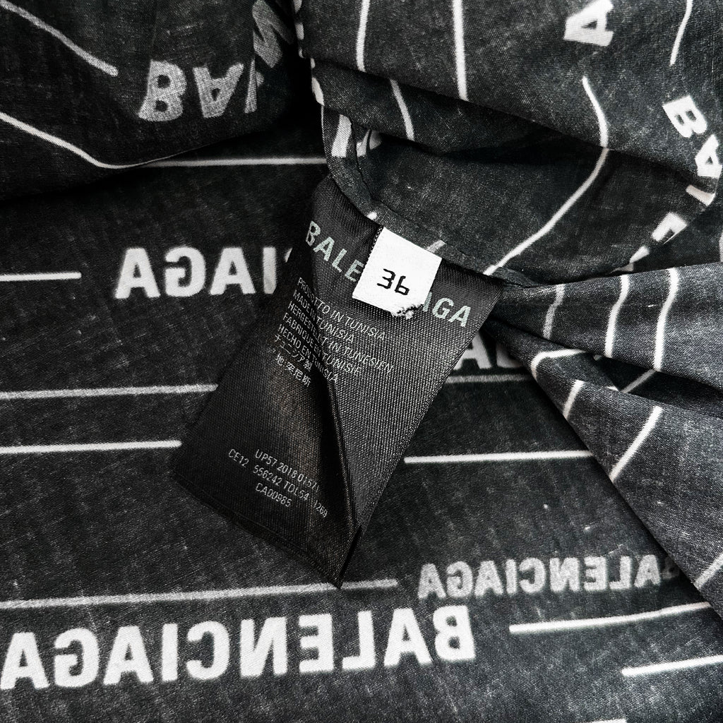 a close-up view of a black and white fabric with the word "BALANCE" printed on it. The fabric appears to be a garment or textile, and there is a label attached to it.