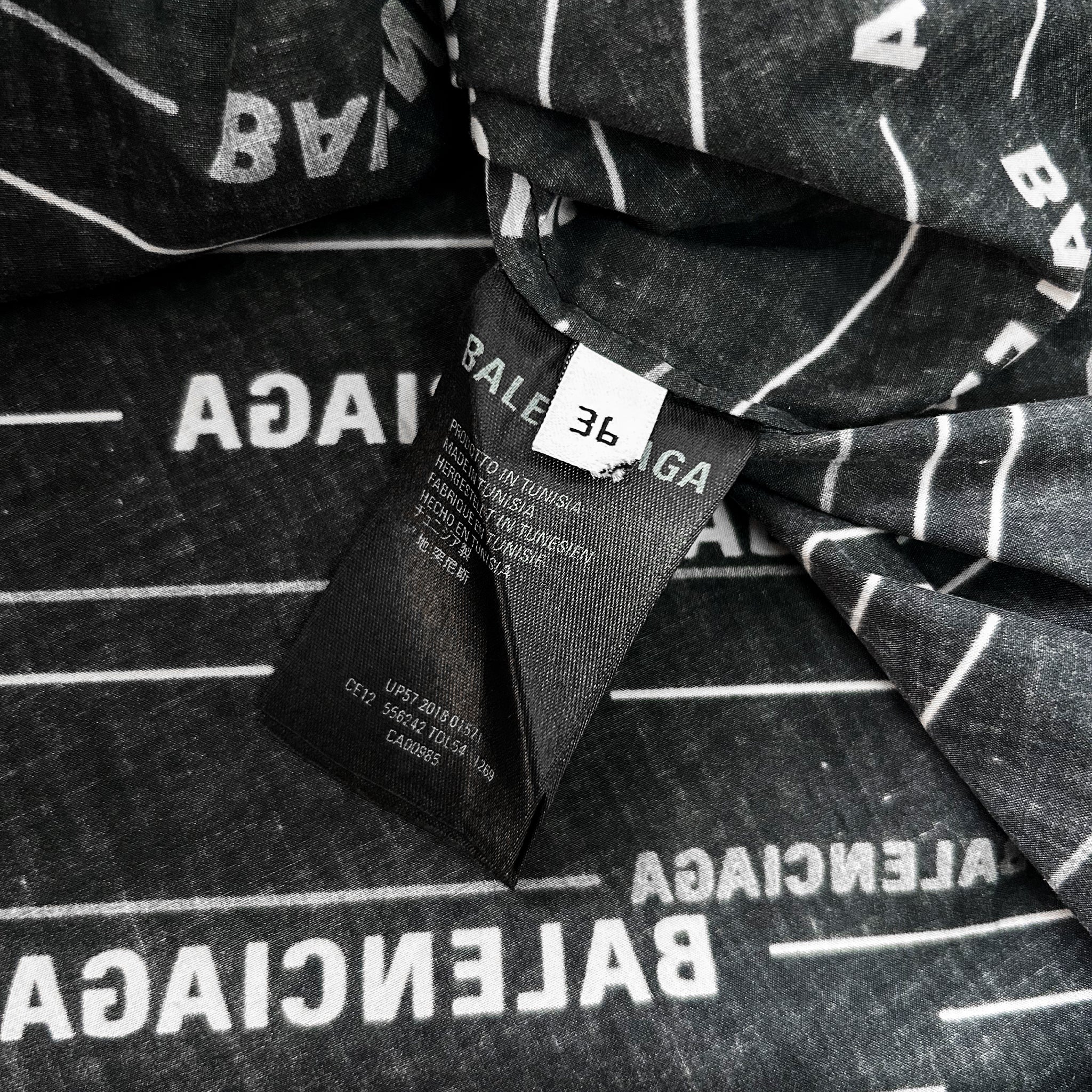 a close-up view of a black and white fabric with the word "BALANCE" printed on it. The fabric appears to be a garment or textile, and there is a label attached to it.