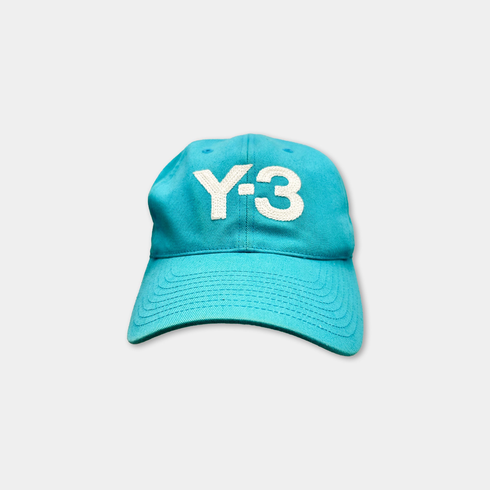 A turquoise baseball cap with the text "Y-3" printed on it.