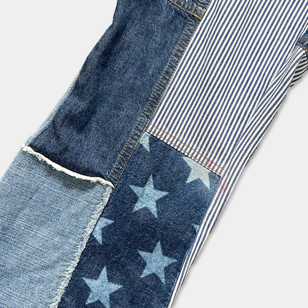 a close-up view of a pair of jeans with a patchwork design. The patchwork consists of denim fabric with blue and white stripes, and stars. The jeans appear to be a mix of different denim pieces, creating a unique and visually interesting design.