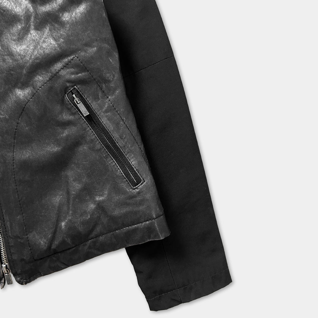 A close-up view of a black leather jacket with a zipper and a black sleeve.