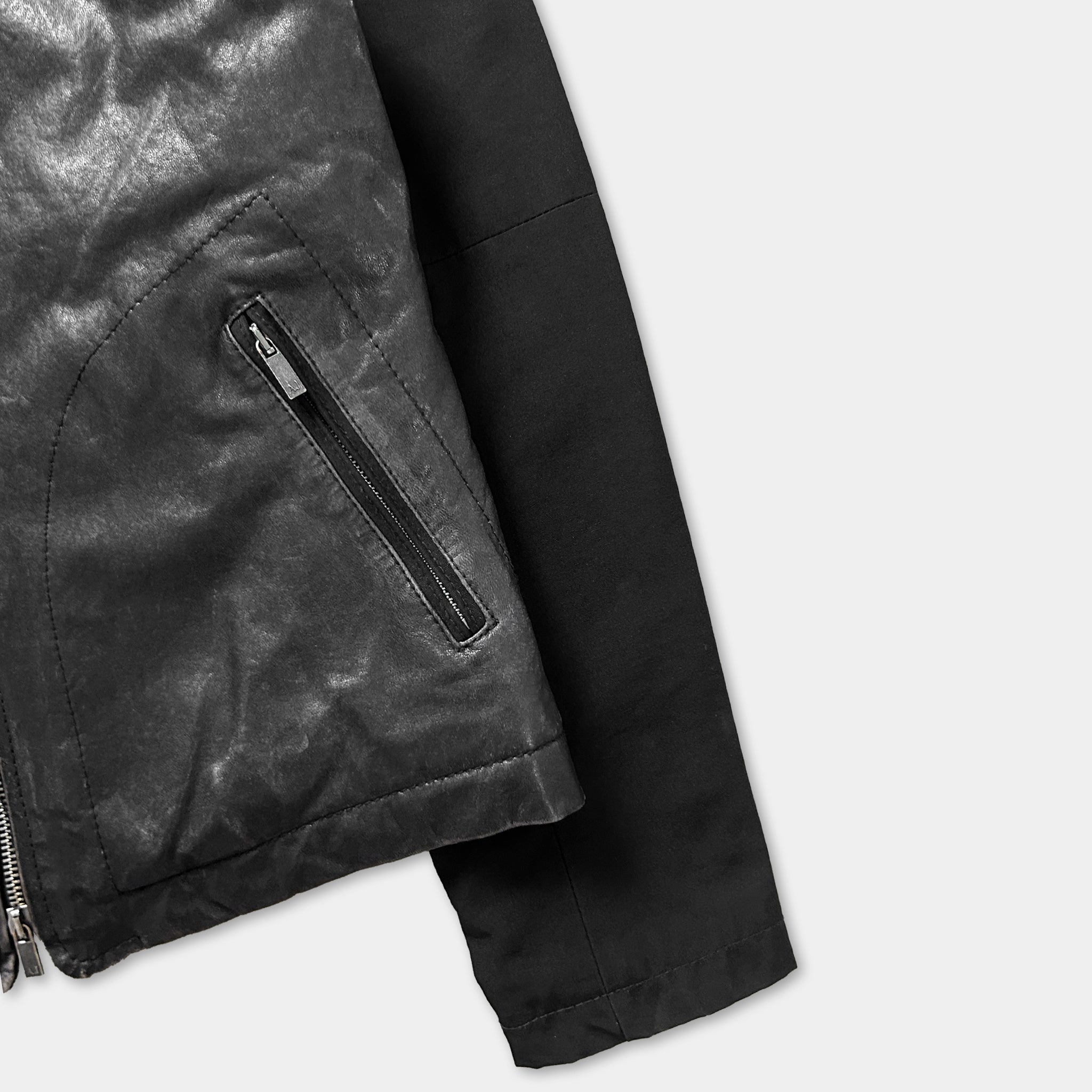 A close-up view of a black leather jacket with a zipper and a black sleeve.