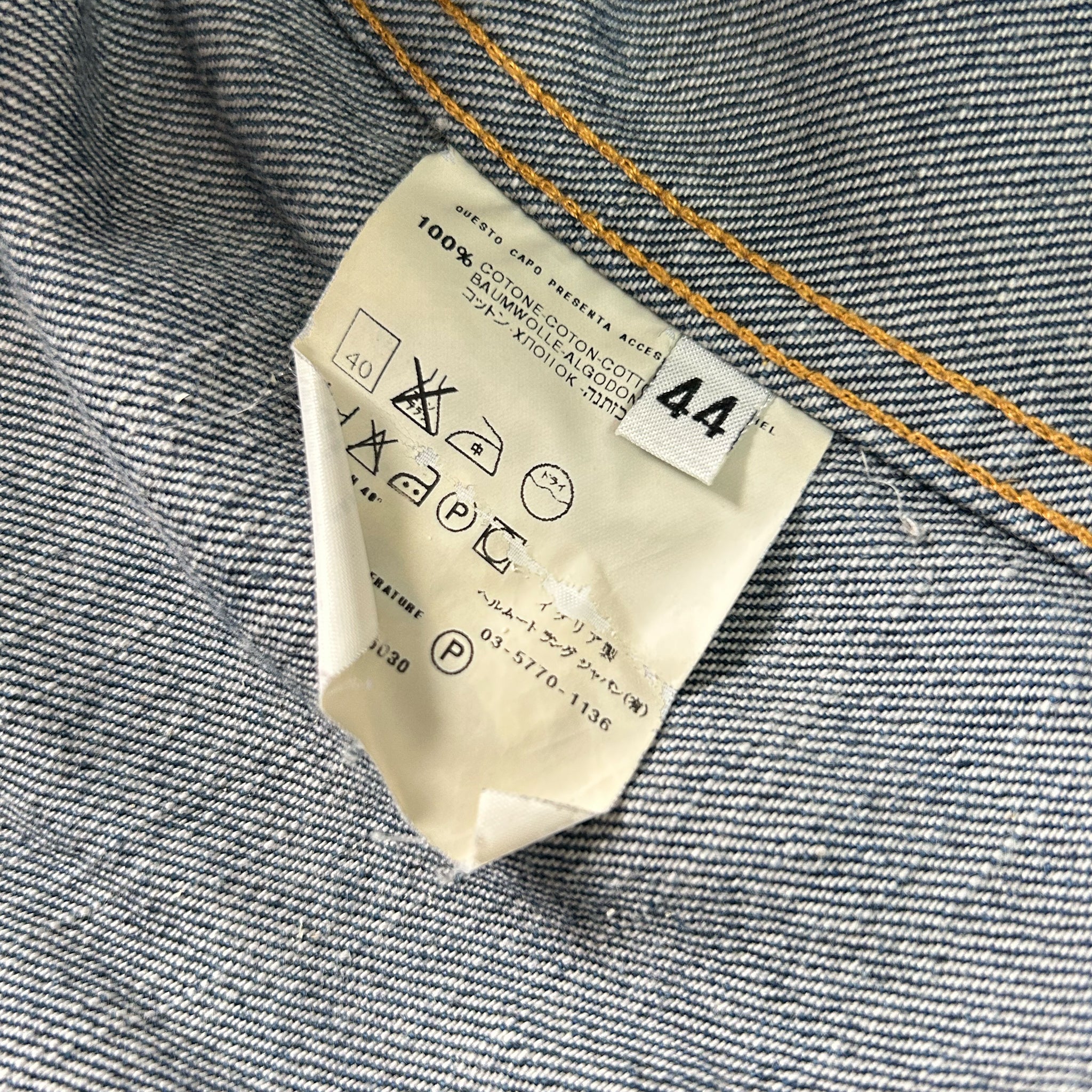 a close-up view of a denim fabric, with a label attached to it. The label appears to be a care label, providing instructions for washing and drying the denim fabric.