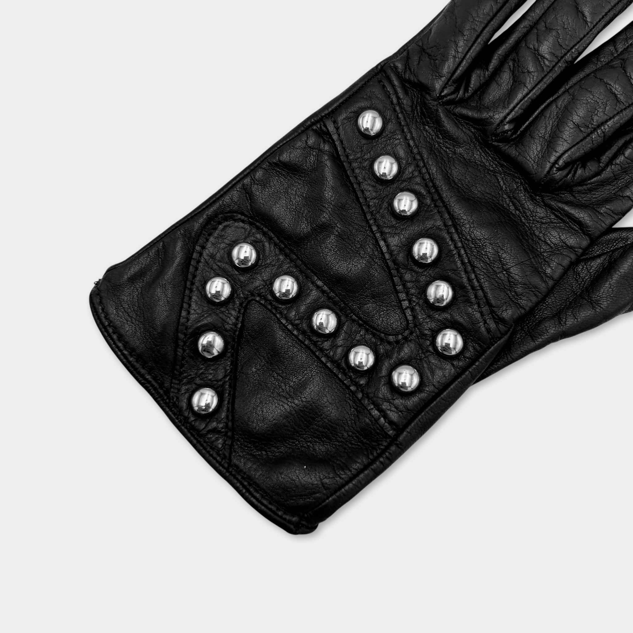 A close-up view of a black leather glove with silver studs on the palm area.