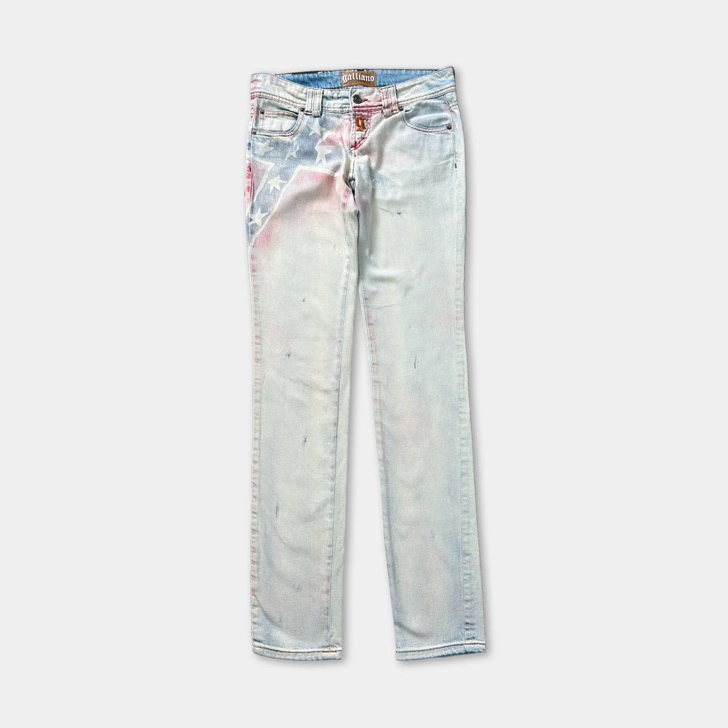 A pair of light blue denim jeans with a pink and white paint splatter on the left leg.