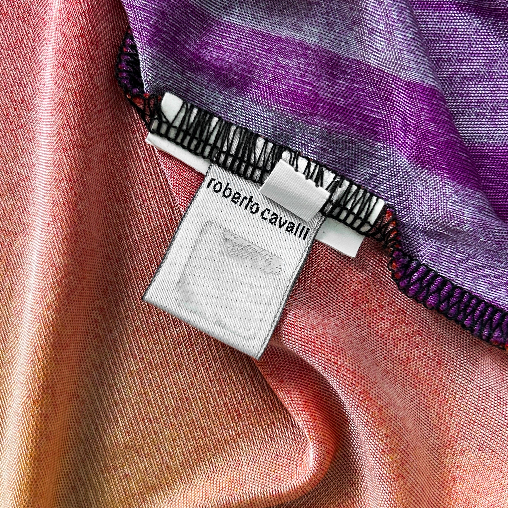a close-up view of a fabric label with text, placed on a colorful fabric with a striped pattern.