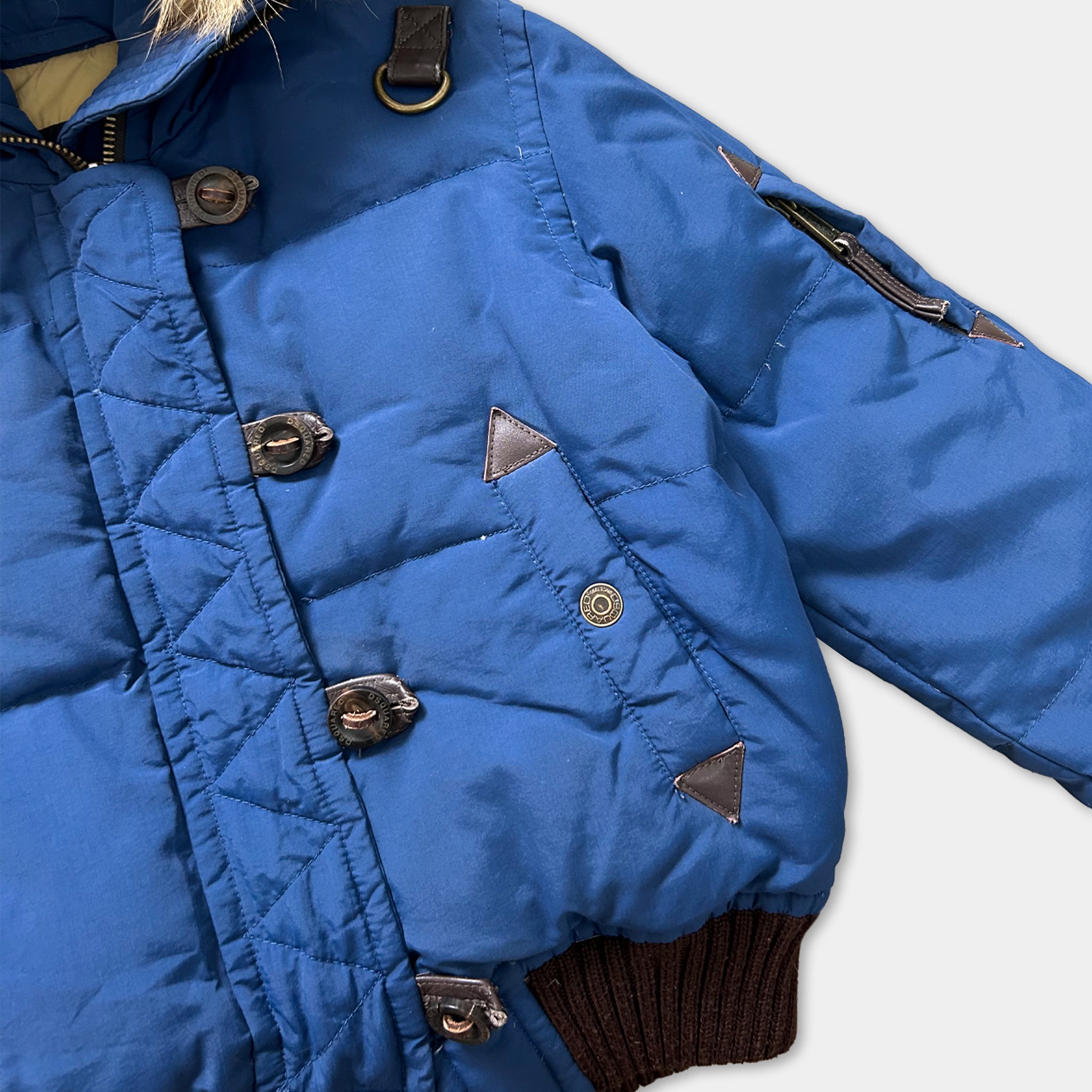 A close-up view of a blue puffy jacket with brown accents, including buttons and a zipper.