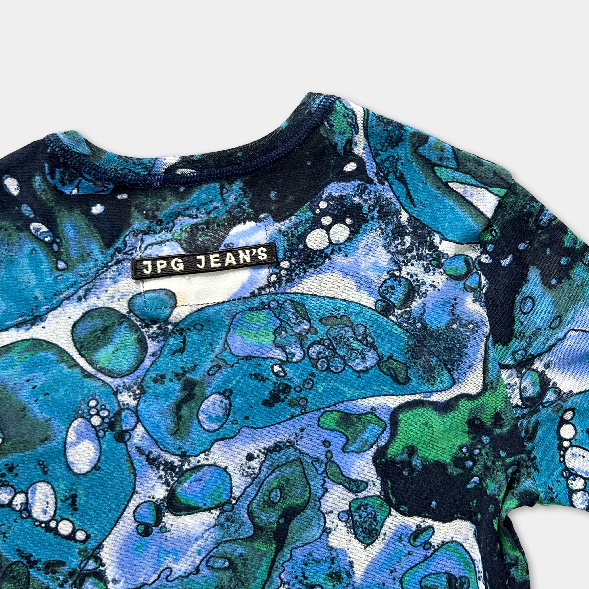 a colorful, abstract pattern on a shirt, featuring various shades of blue, green, and white.