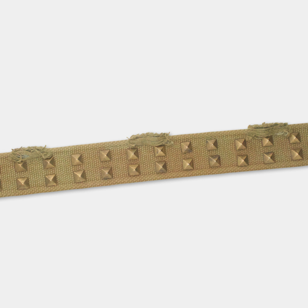 A beige fabric with small square metal studs sewn onto it.