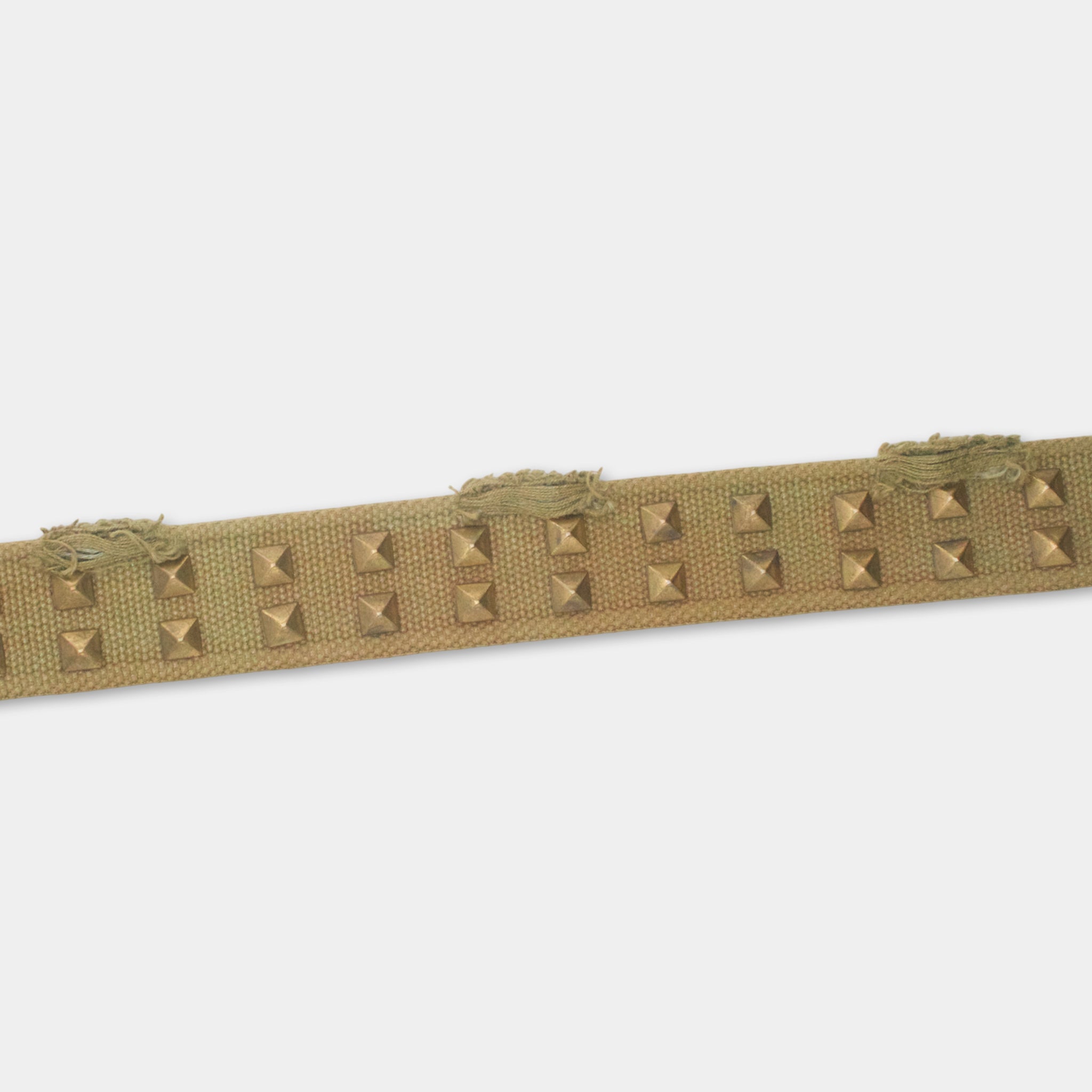A beige fabric with small square metal studs sewn onto it.