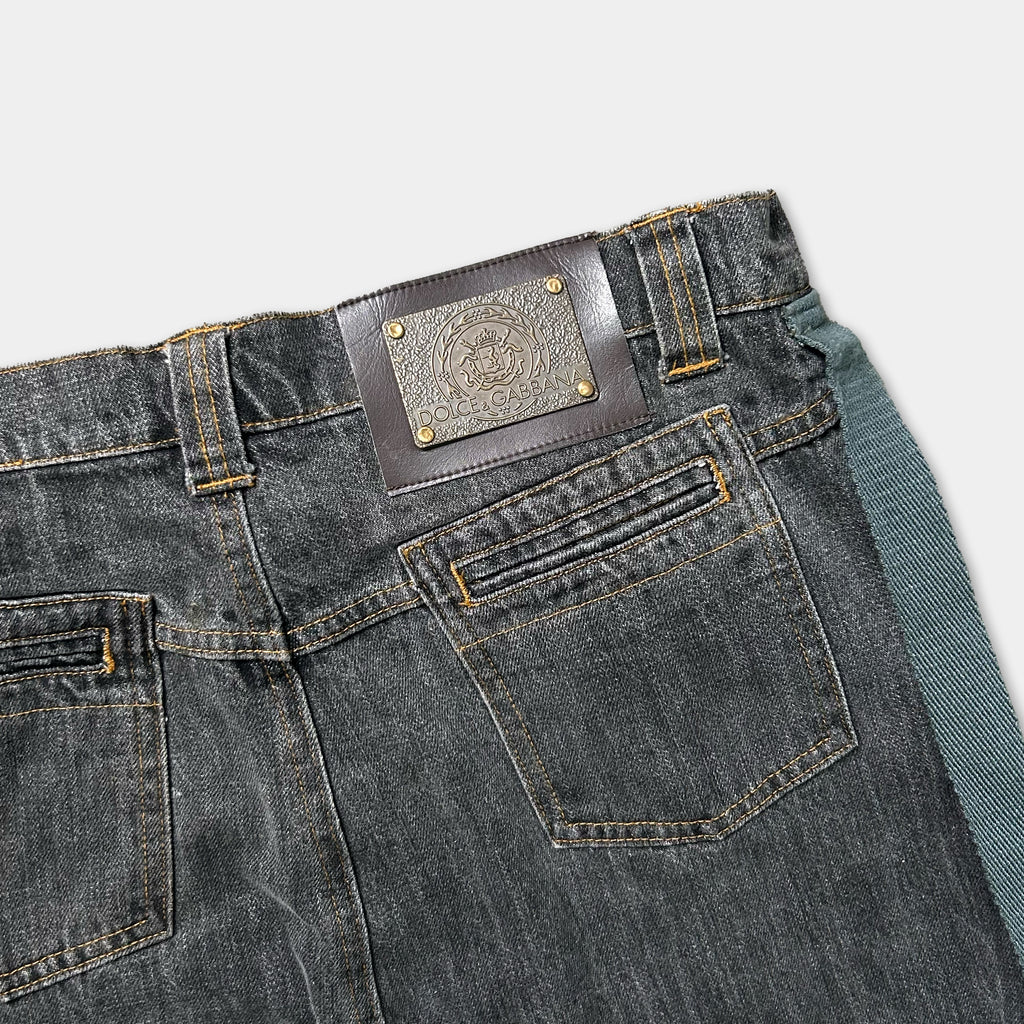 A pair of black denim jeans with a leather patch on the back pocket.